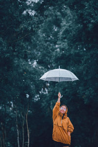 Girl holding umbrella standing in forest