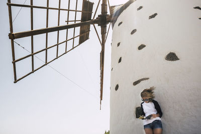 Mature woman standing against traditional windmill