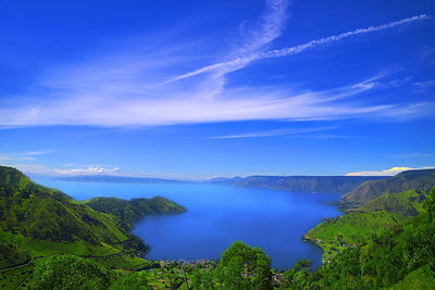 Scenic view of sea and mountains against blue sky