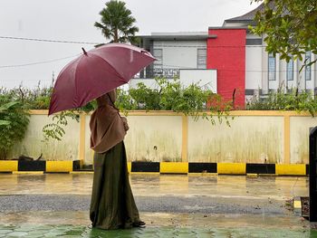 Woman holding umbrella standing during rainy season
