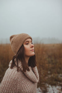 Portrait of a women standing in a foggy late autumn winter field against sky with negative space