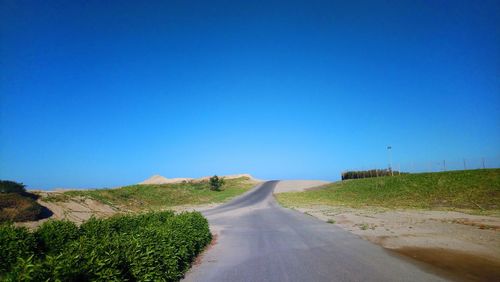 Road amidst landscape against clear blue sky