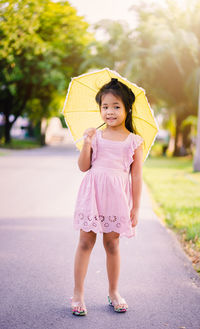 Portrait of girl with umbrella standing on road
