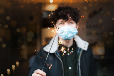 Portrait of woman wearing mask holding sparkler