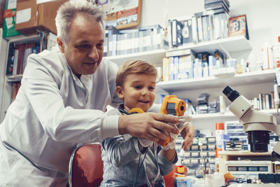 Science teacher and student using infrared thermometer in engineering laboratory.