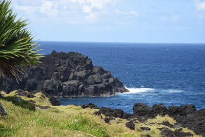 Scenic view of rocks by sea against sky