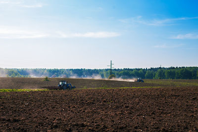 Tractor on agricultural field against blue sky