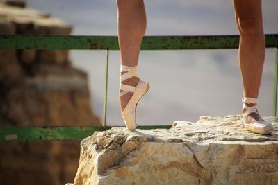 Low section of ballet danger standing tiptoe on rock against mountain
