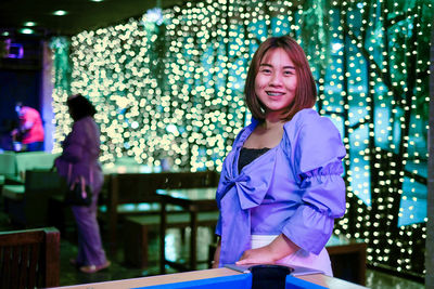 Portrait of smiling woman at illuminated restaurant