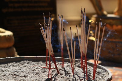 Close-up of burning incense in container at temple