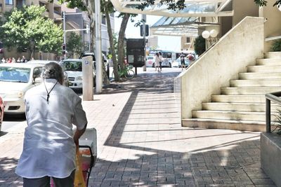 Rear view of people walking on street in city