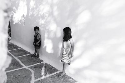 Siblings leaning on white wall