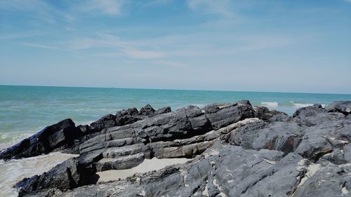 Rock formation on beach against sky