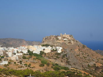 Buildings on mountain against clear blue sky