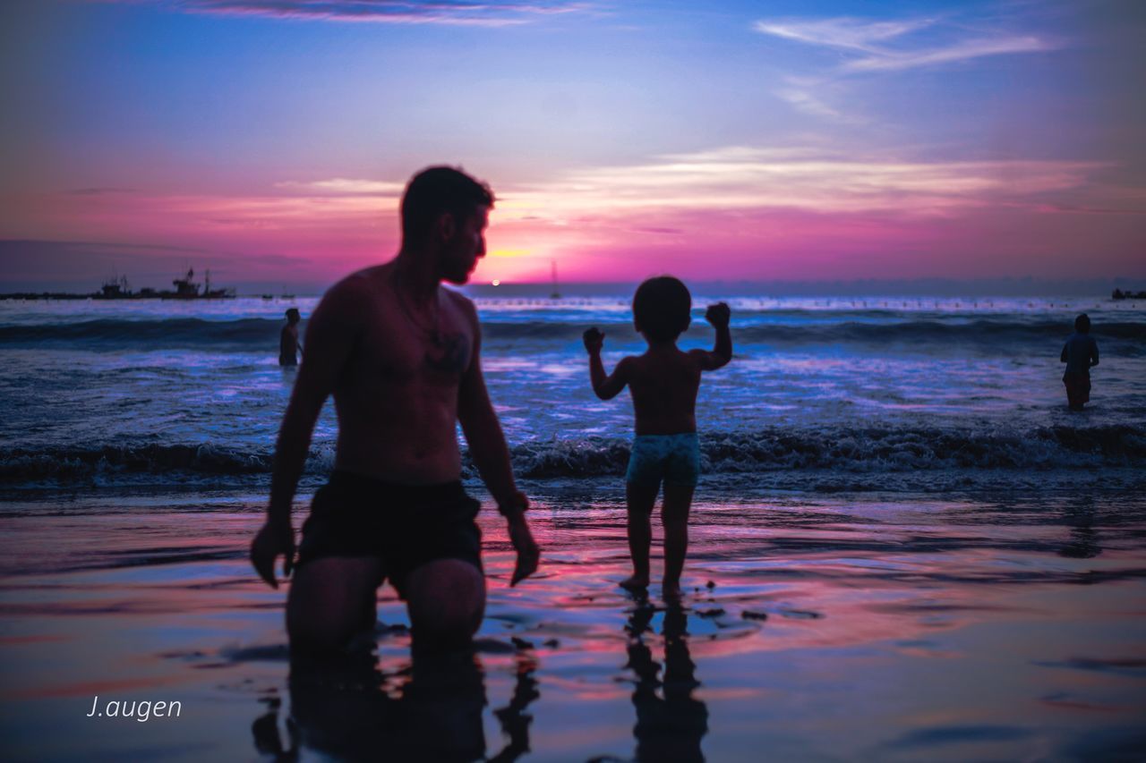 REAR VIEW OF SILHOUETTE FRIENDS STANDING ON BEACH DURING SUNSET