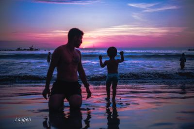 Silhouette friends standing on beach against sky during sunset