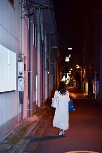 Rear view of woman walking on building at night