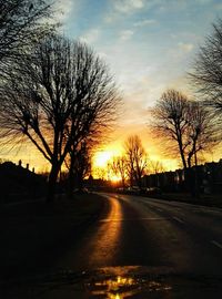 Road amidst trees against sky during sunset