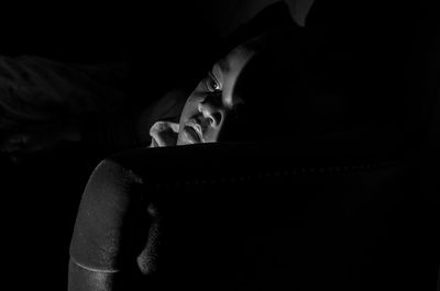 Portrait of man relaxing on bed in darkroom