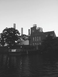 Buildings by river against clear sky