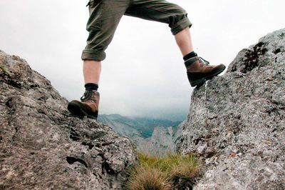 Low section of man on rock against sky