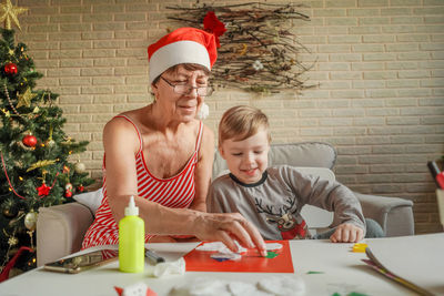 Grandmother with grandson making craft product on table at home