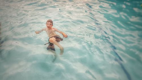 High angle portrait of cute boy swimming in pool