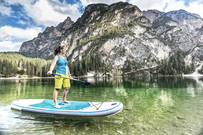 Woman paddleboarding in lake against dolomites mountain