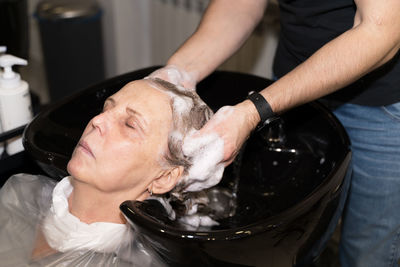 An elderly woman washes her hair in a beauty salon