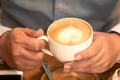 Cropped image of hand holding coffee cup