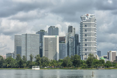 Modern buildings by river against sky in city