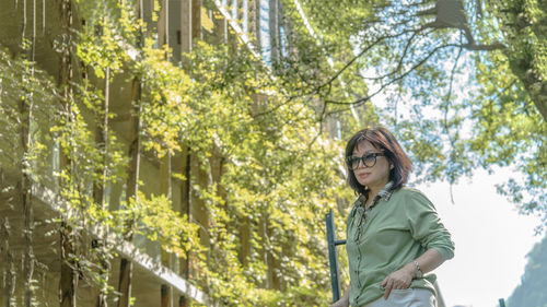 Woman standing by plants against trees