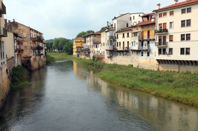 Buildings by river against sky