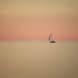 Sailboat in sea against sky during sunset