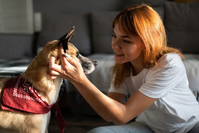 Rear view of woman with dog sitting at home