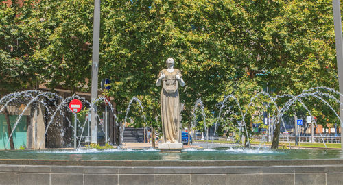 Statue by street against trees in city