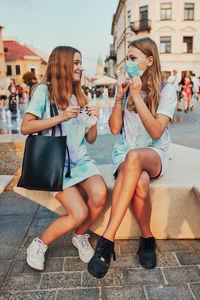 Young women spending time together sitting in the city center. girls wearing the face masks