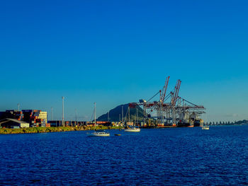 Sailboats in sea against clear blue sky