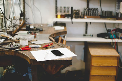 Mobile phone and document on workbench in jewelry workshop