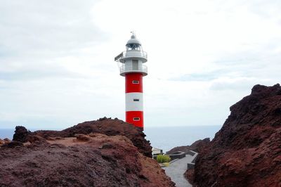 Lighthouse by sea against sky