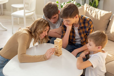 Family , in room play a board game made of wooden rectangular blocks