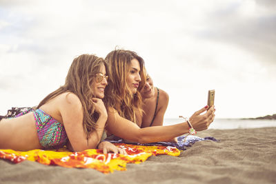 Happy friends wearing bikini while enjoying together at beach