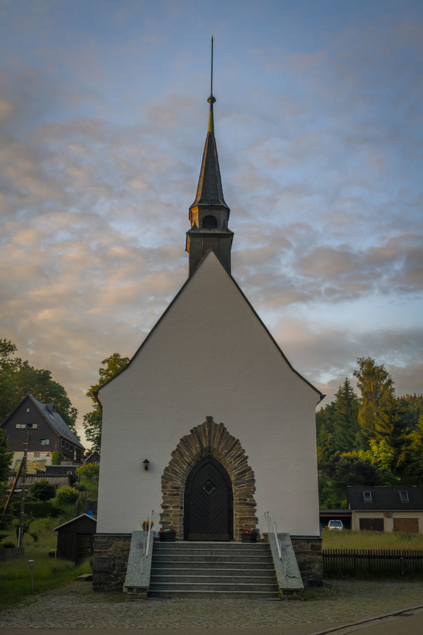 architecture, religion, built structure, place of worship, belief, building exterior, sky, building, spirituality, nature, cloud, no people, tower, history, the past, travel destinations, catholicism, plant, cross, tree, outdoors, spire, steeple, cemetery, travel