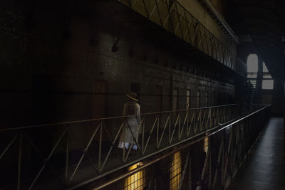 Rear view of man walking on illuminated bridge at night