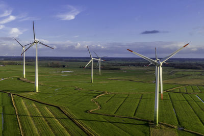 Wind turbines on field against sky