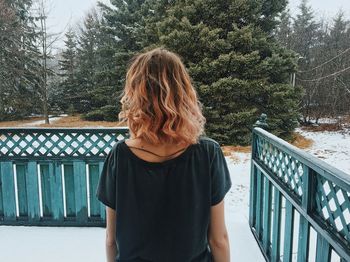 Rear view of woman standing against railing in winter