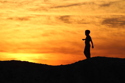 Silhouette man standing against sky during sunset