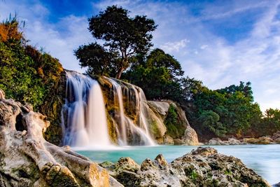 Scenic view of waterfall against sky