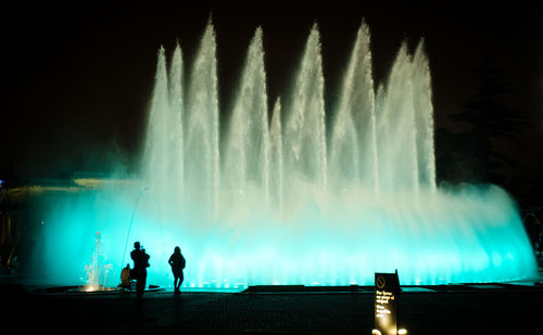 Panoramic shot of silhouette man standing against illuminated sky at night