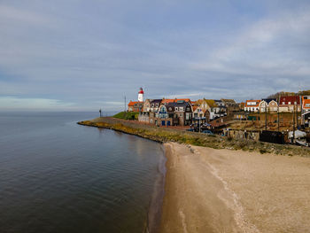 Houses by sea against sky in city